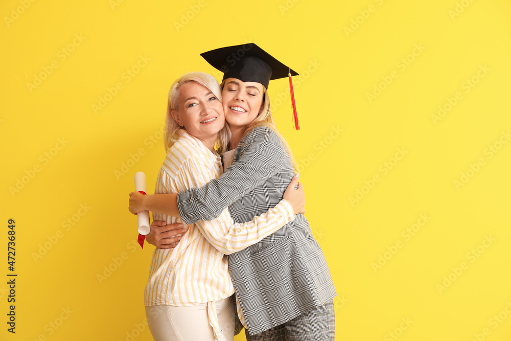 Happy female graduation student with her mother on color background