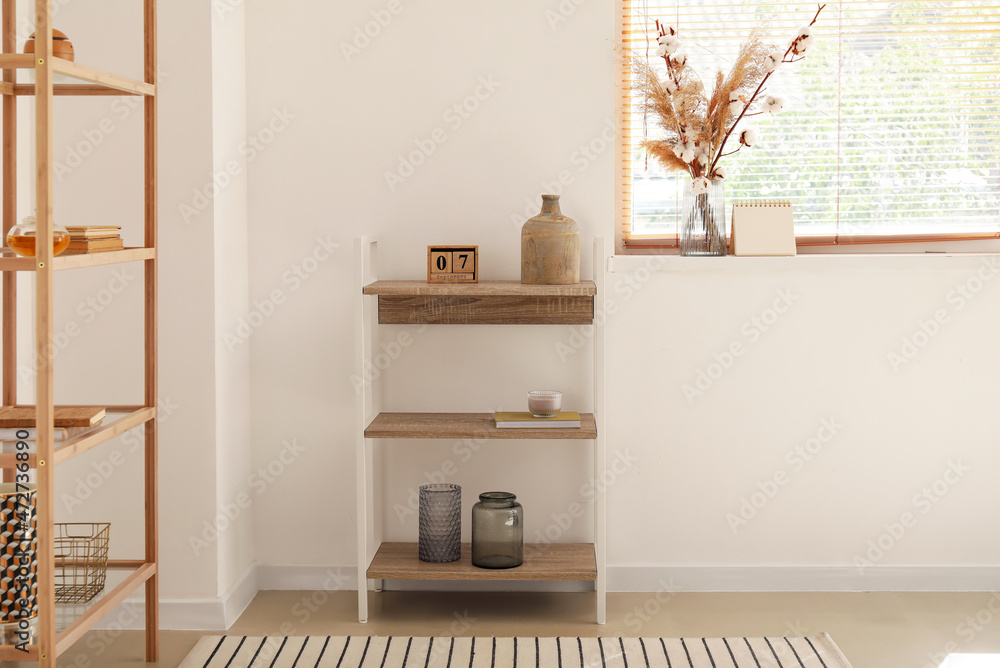 Interior of room with shelving unit, pampas grass and cotton branches in vase