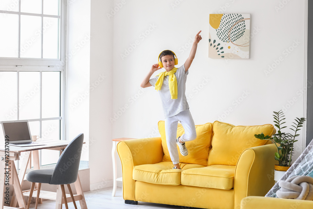 Cute little boy listening to music and dancing at home