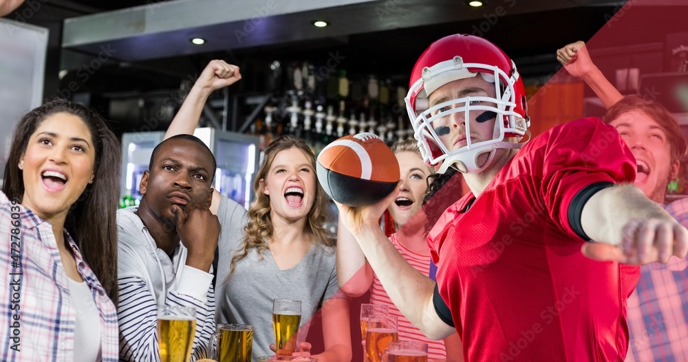 Male american footballer about to throw ball against excited spectators at bar