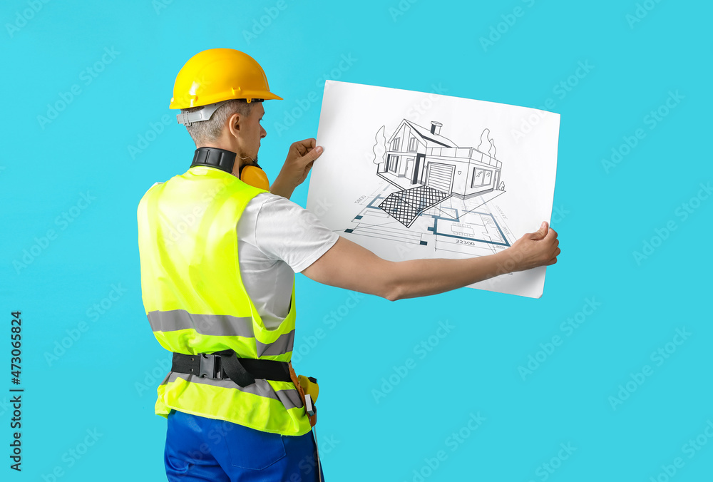 Male builder with drawing on color background