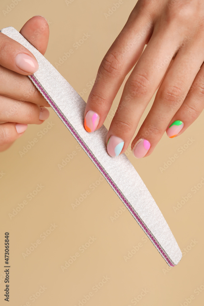 Woman doing manicure on beige background