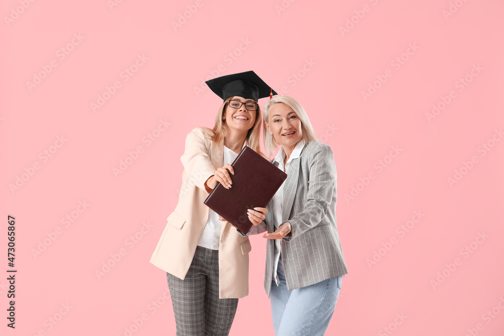 Happy female graduation student with her mother on color background