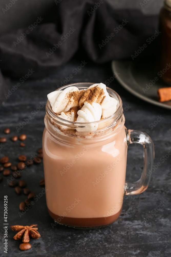 Mason jar of tasty coffee with cinnamon on black background