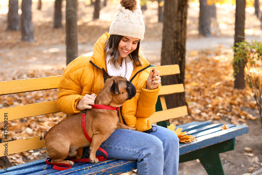 年轻女子与可爱的法国斗牛犬在秋季公园