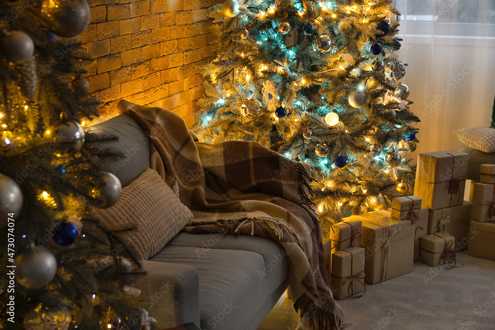 Interior of dark living room with Christmas trees and sofa