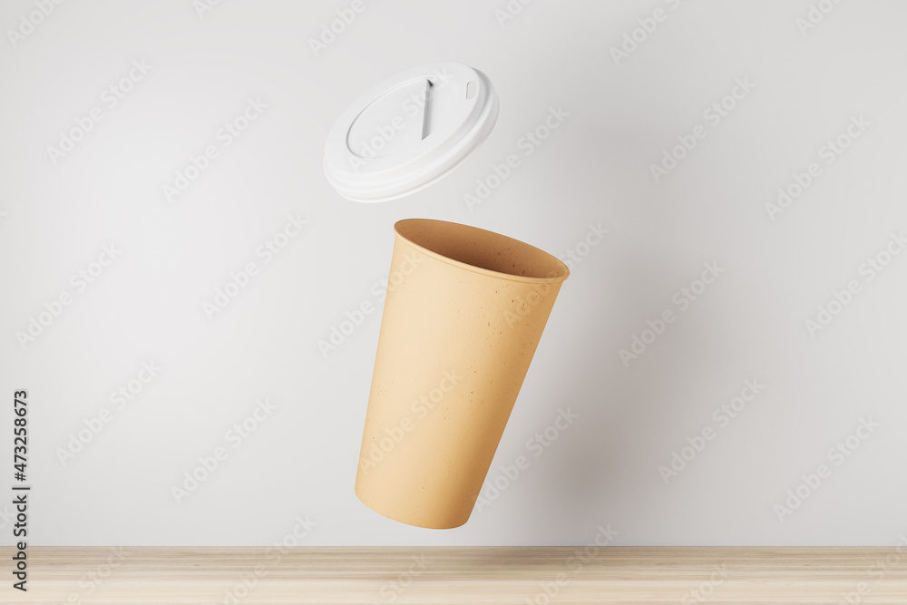 Empty yellow take away coffee cup on white background and wooden surface. Advertisement and mock up 