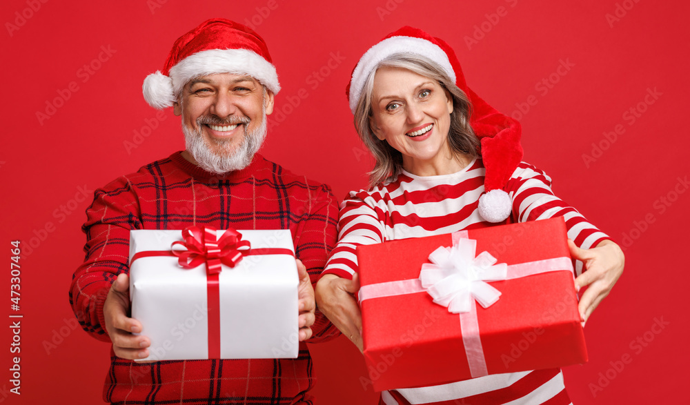 cheerful senior family couple in love  dressed in red Santa hats  holds a Christmas gifts and laughi