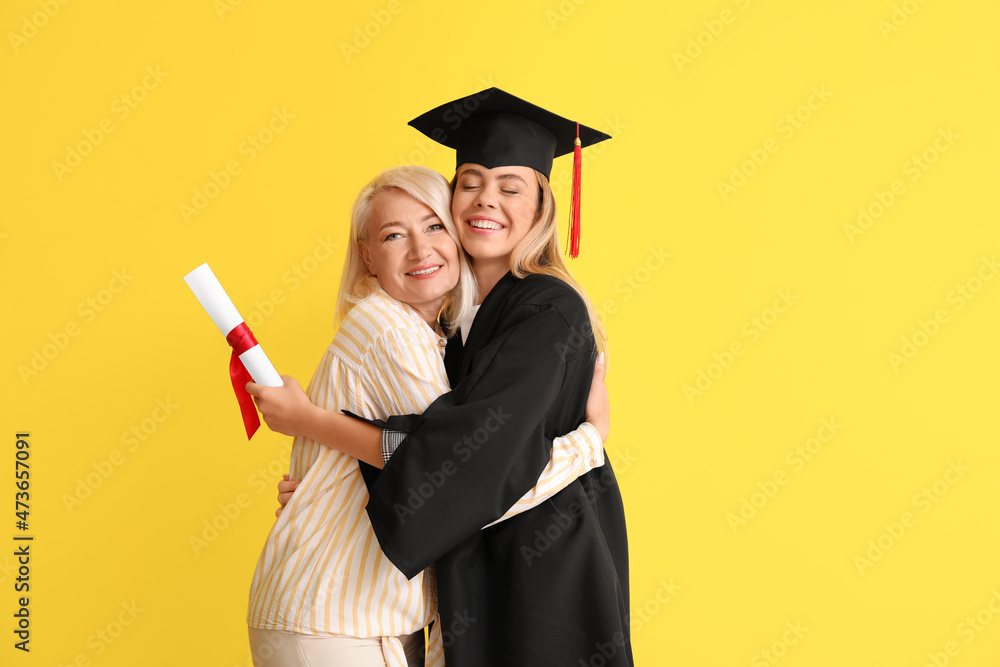 Happy female graduation student with her mother on color background