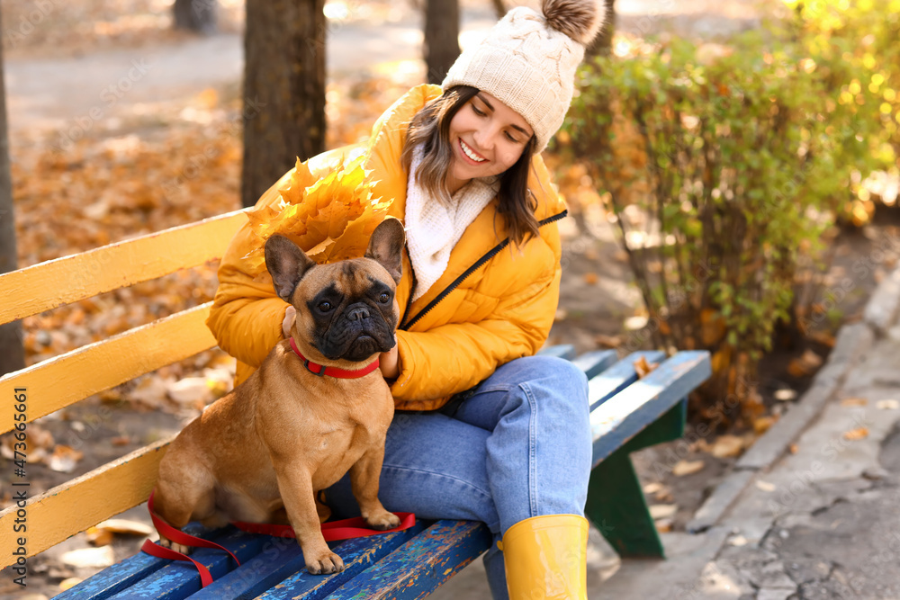 年轻女子与可爱的法国斗牛犬在秋季公园