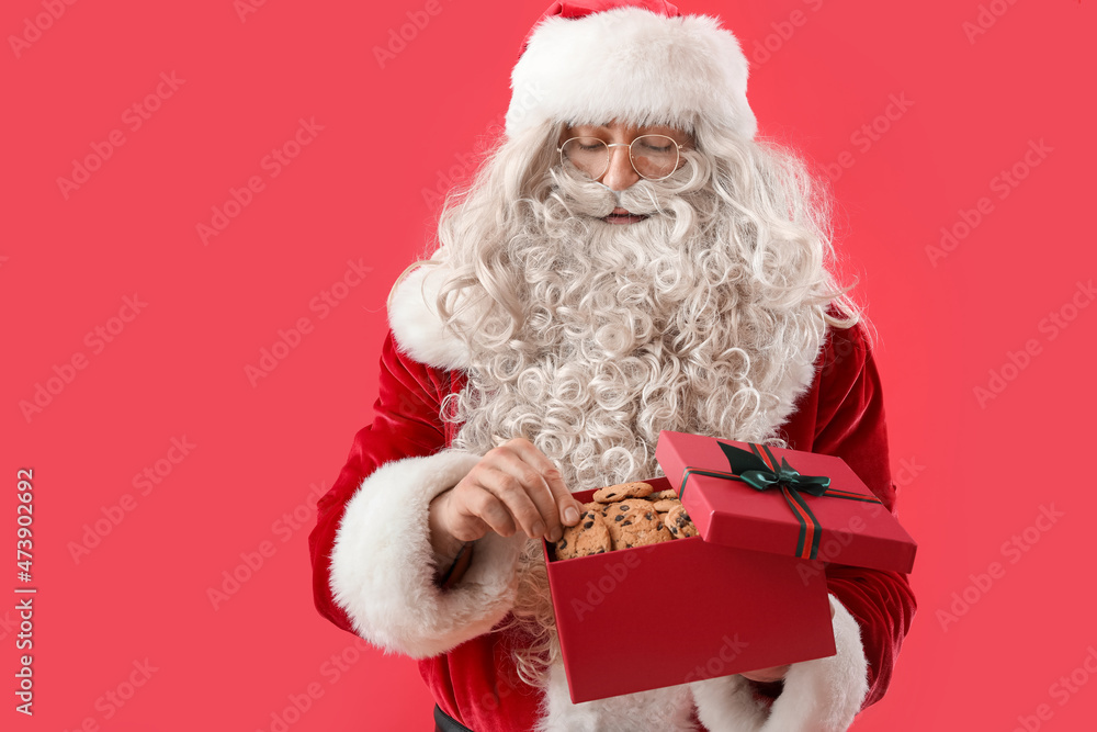 Santa Claus with tasty cookies in gift box on color background