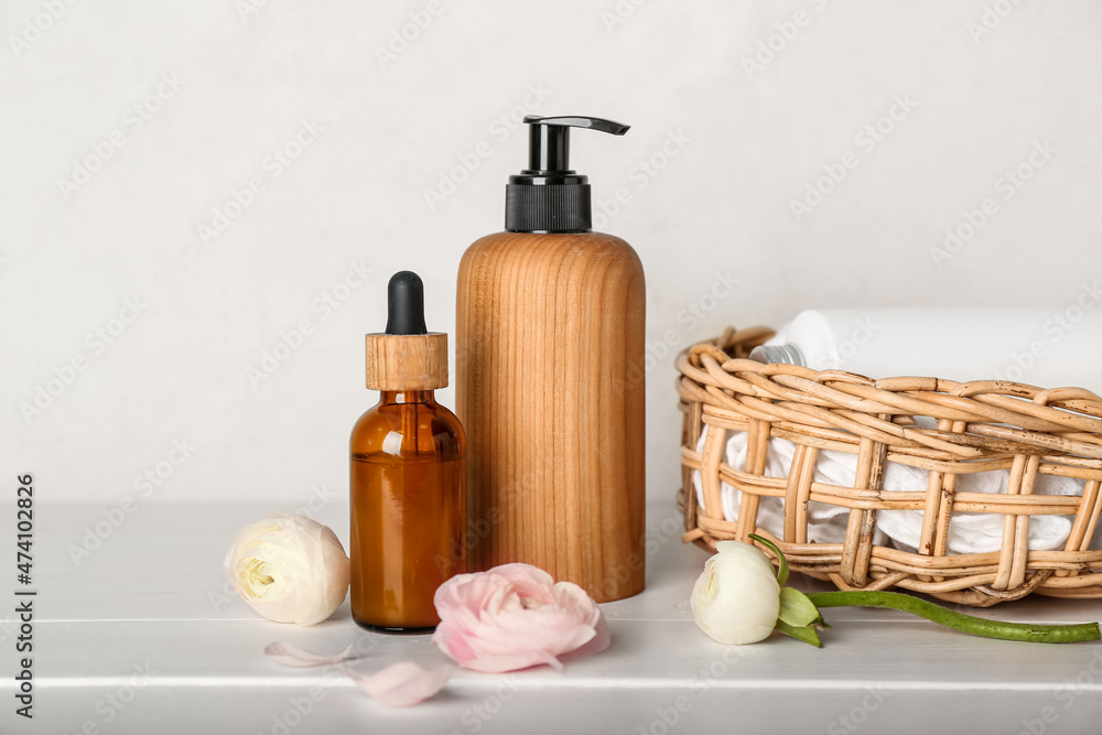 Bottles with cosmetics and ranunculus flowers on wooden table