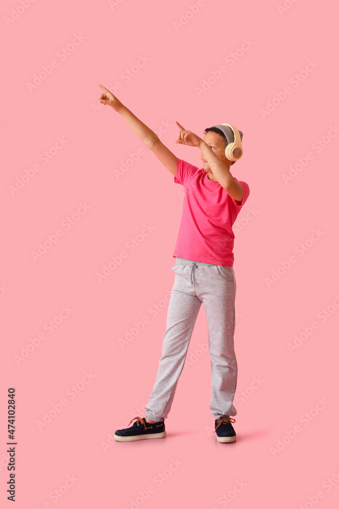 Cool dancing little boy with headphones on color background