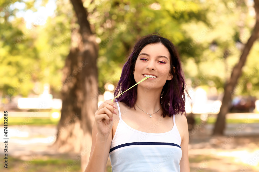 Young woman with purple hair chewing gum in park