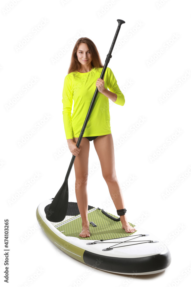 Sporty young woman with board for sup surfing and oar on white background