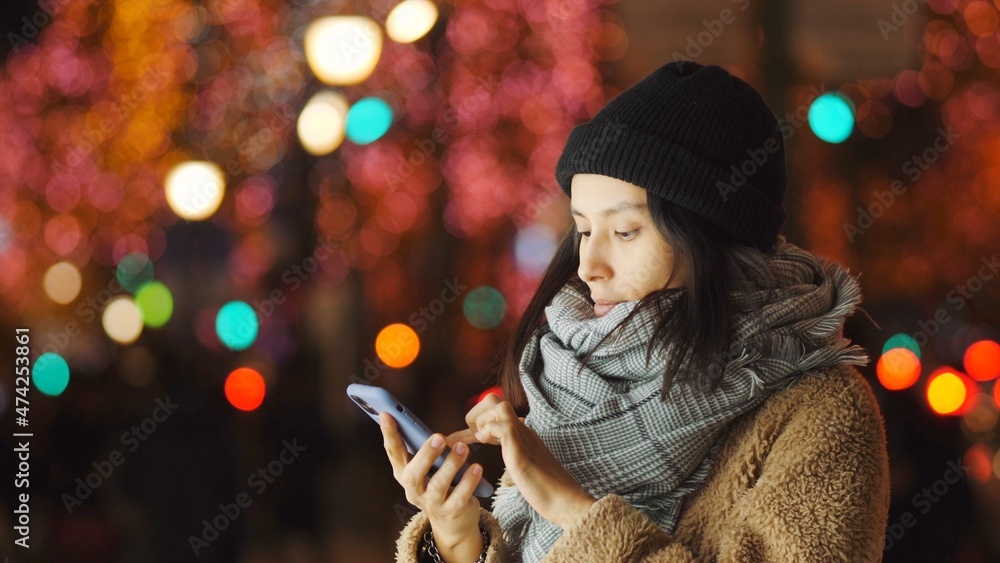 Young Woman Walking And Using Smartphone In The Evening Winter Street. Social Networking New Year Ch