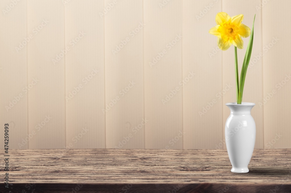 Beautiful vase with flowers against a wall on the desk