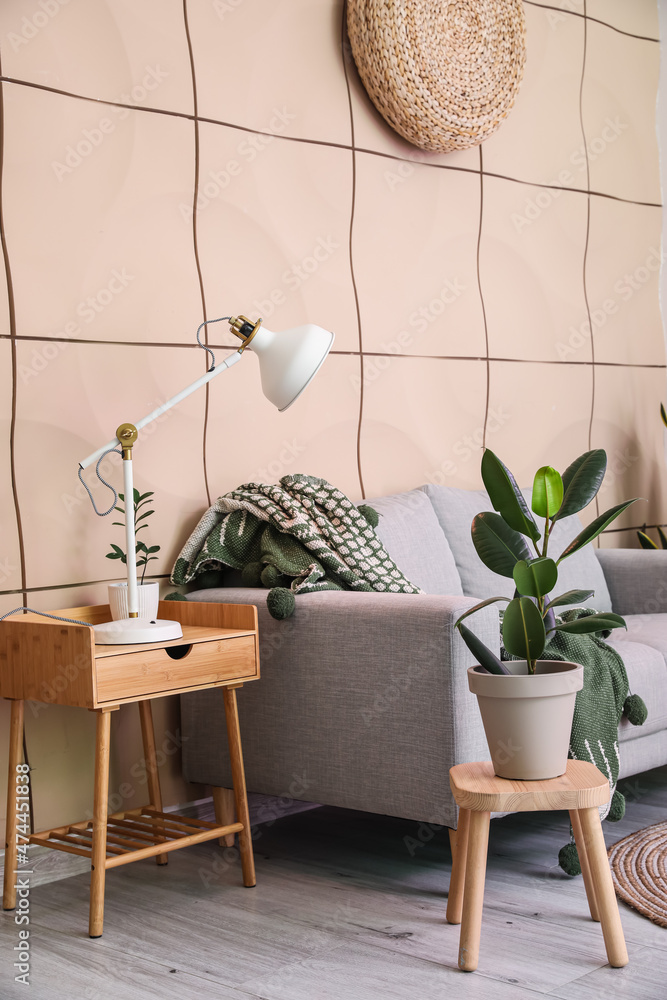 White lamp and flowerpot on wooden table near beige wall in living room