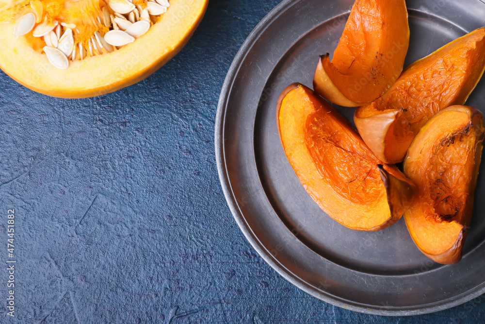 Plate with baked pumpkin pieces on black background, closeup