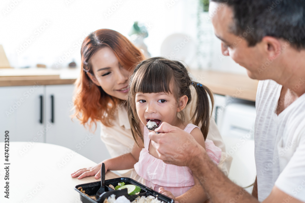 亚洲有魅力的父母在厨房给可爱的宝贝女儿喂食