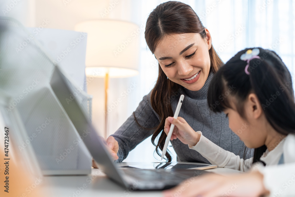 亚洲小女孩在家和妈妈一起学习网课。