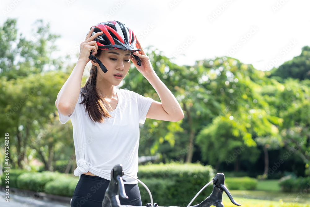 亚洲年轻运动女性戴着头盔，准备骑自行车。