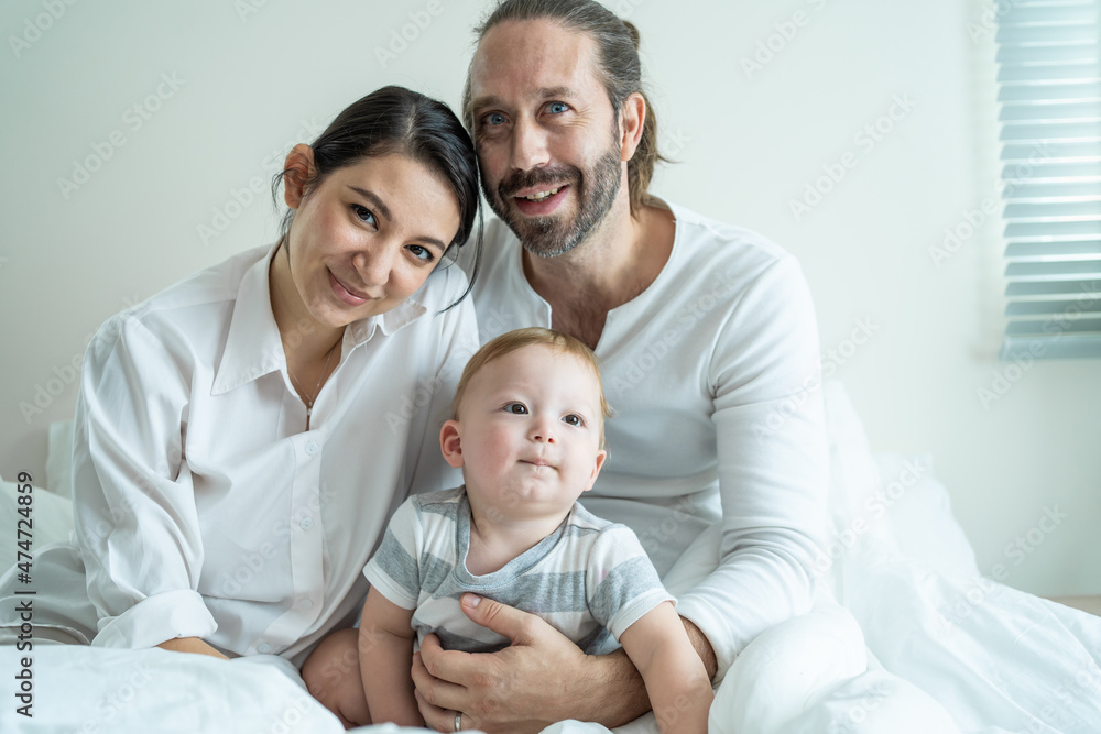 Portrait of Caucasian happy family smiling, look at camera in bedroom.