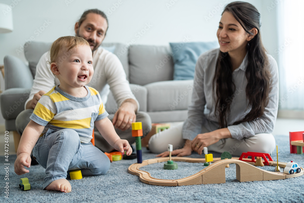 Caucasian happy loving parent play with baby toddler in living room.