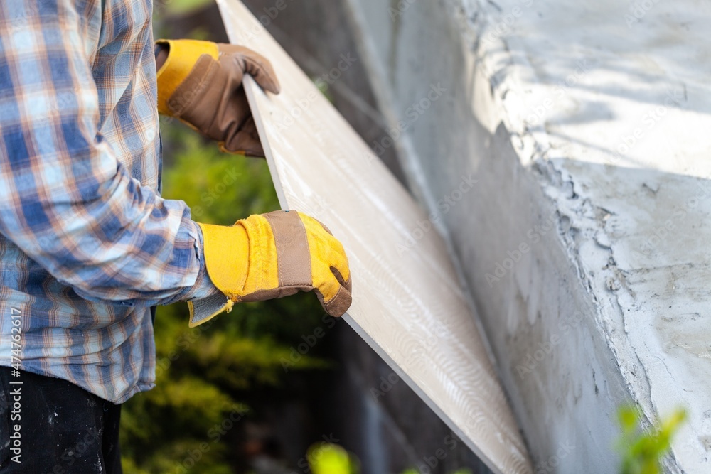 A worker with gloves lays down and dismantles the ceramic tiles of the stairs