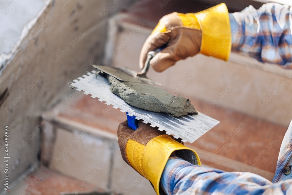 A worker with gloves lays down and dismantles the ceramic tiles of the stairs