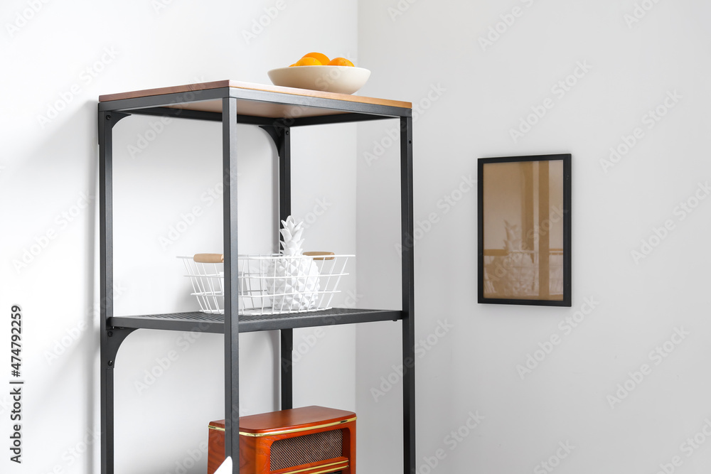 Blank frame and shelving unit with decor near light wall