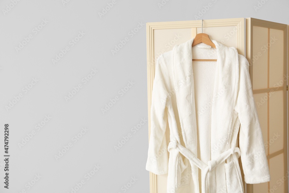 Folding screen with bathrobe near light wall