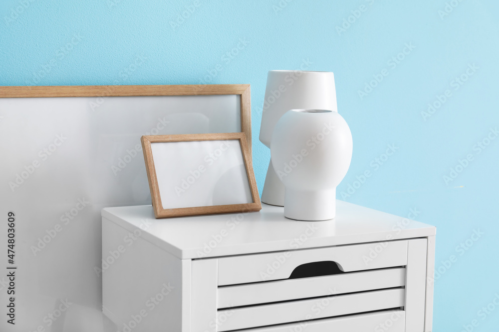 White table with vases and blank frames near blue wall