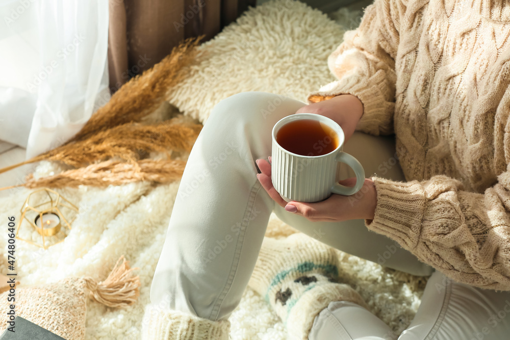 年轻女人在房间里捧着一杯美味的茶