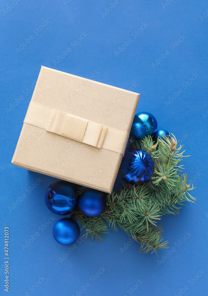 Composition with Christmas gift box, balls and fir branches on blue background