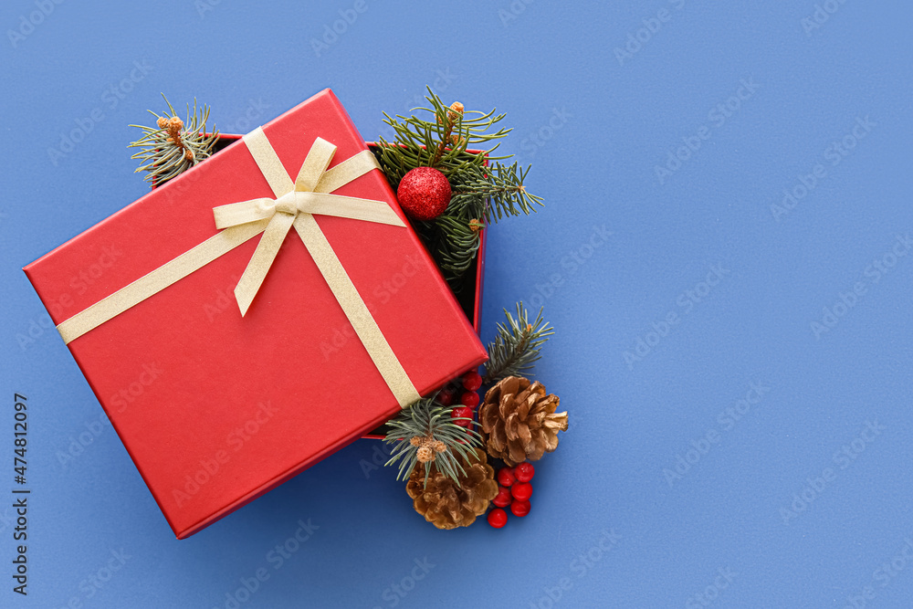 Composition with Christmas gift box, cones and fir branches on blue background