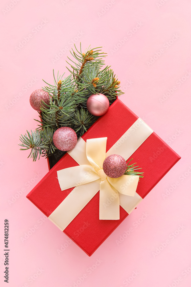 Composition with Christmas gift box, balls and fir branches on pink background