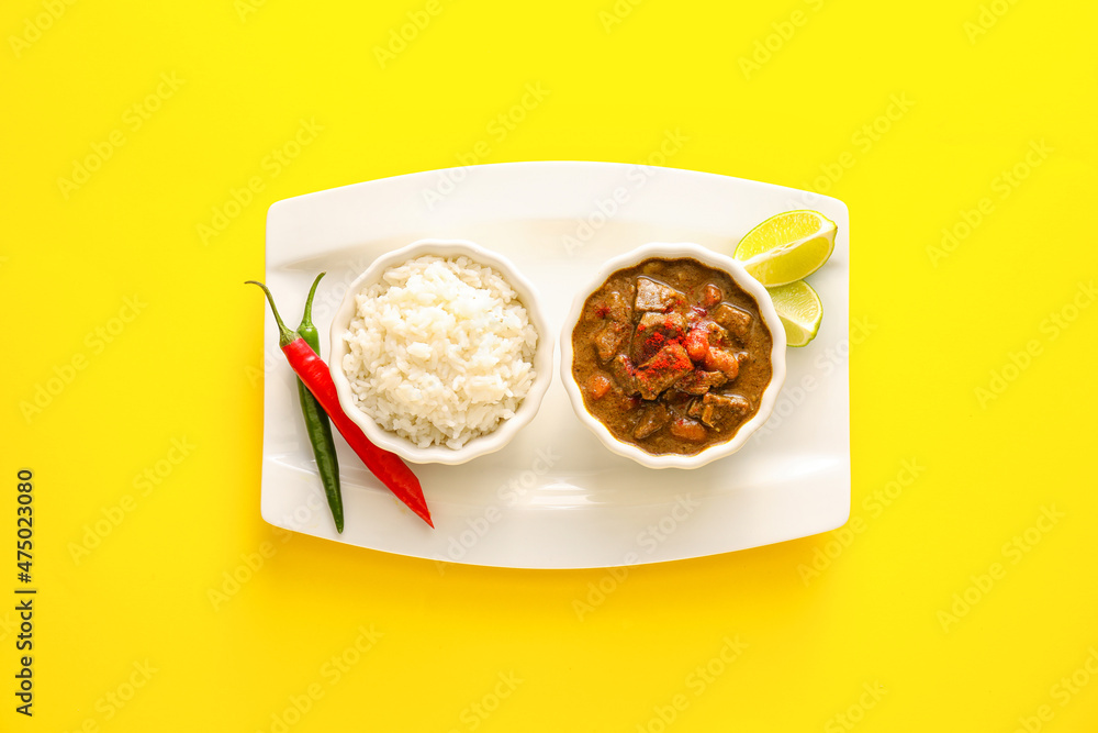 Bowls with tasty beef curry and rice on color background