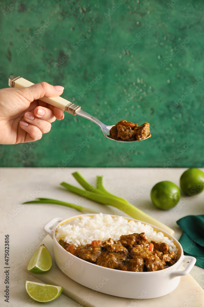 Woman eating tasty beef curry from dish on table