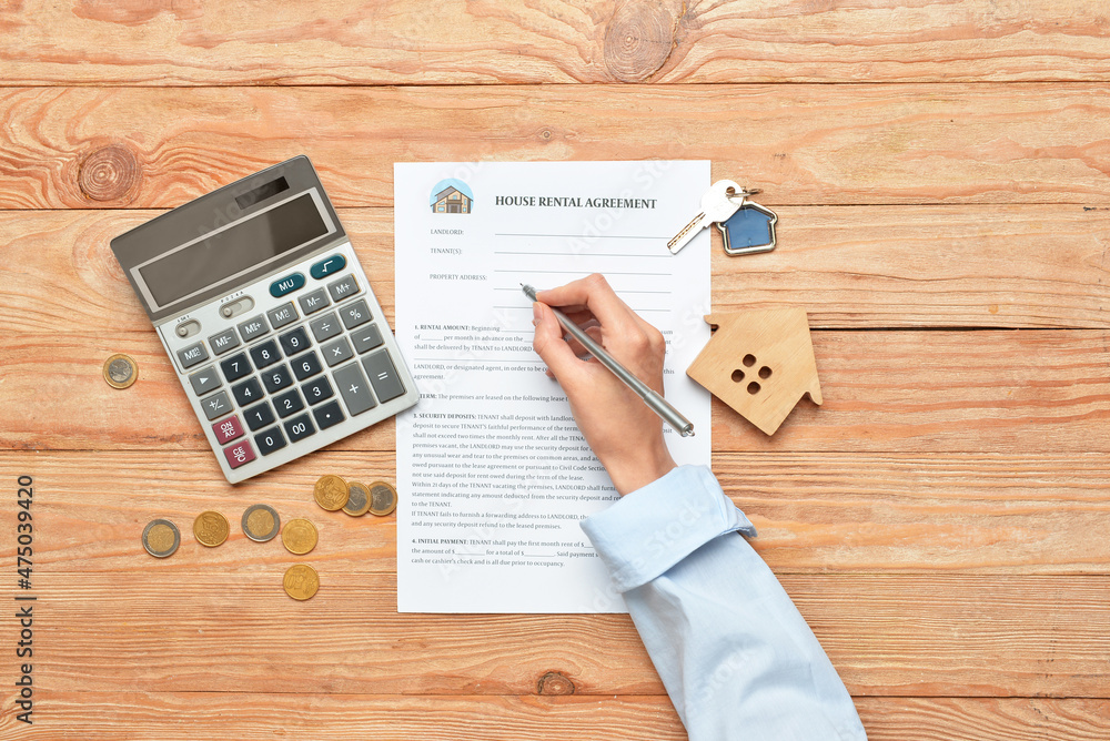 Woman filling in house rental agreement on wooden background