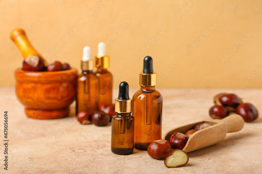 Bottles of essential oil and fresh chestnuts on table