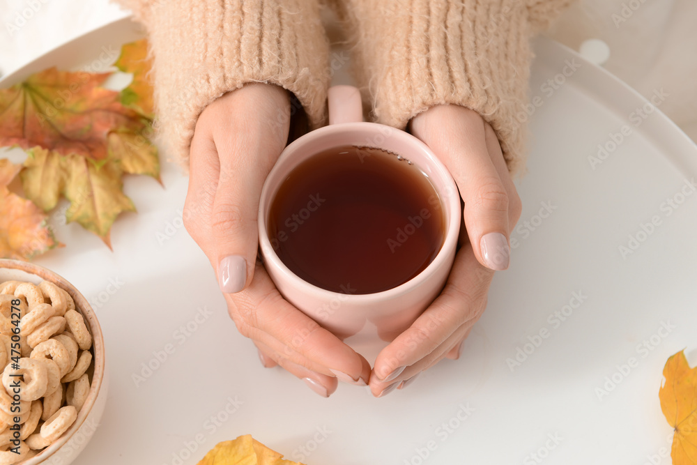 秋天的一天，在白桌子上喝着一杯热茶的女人，特写