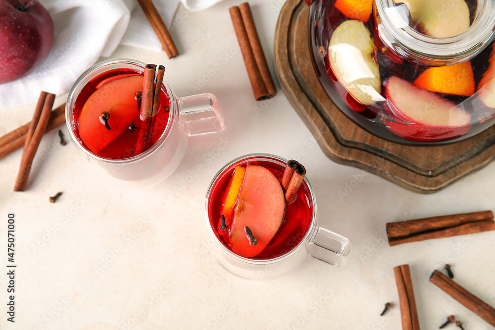 Glass cups of tasty fruit tea with cinnamon on white background