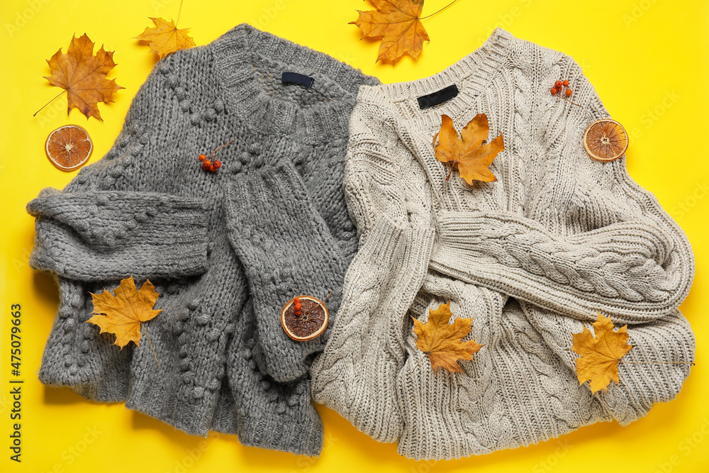 Warm knitted sweaters and autumn decor on yellow background