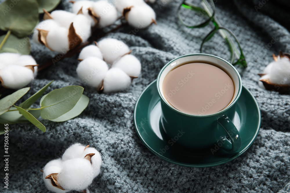 Cup of coffee, cotton flowers and eucalyptus branch on fabric background