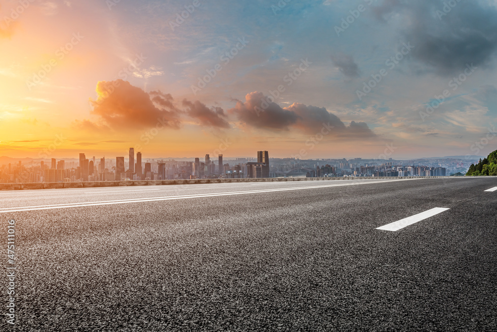 Empty asphalt road with modern city skyline and buildings at sunrise