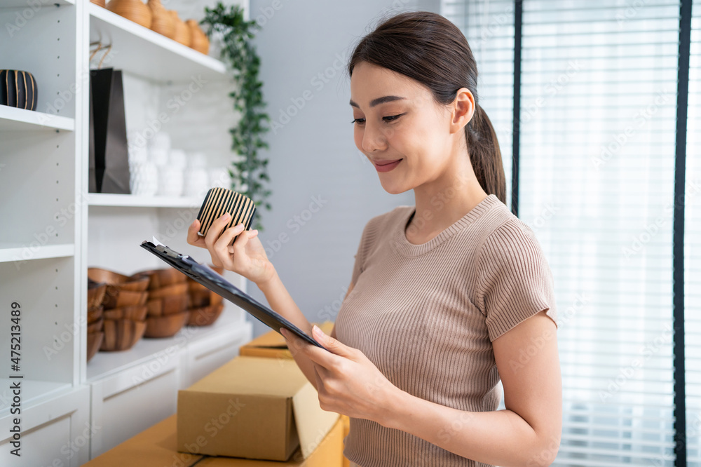 Asian beautiful woman check vase goods order for customer from shelf. 