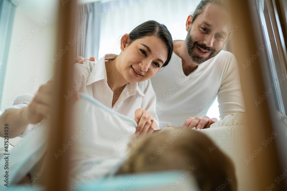 高加索父母在家里的卧室里照顾熟睡的男婴。