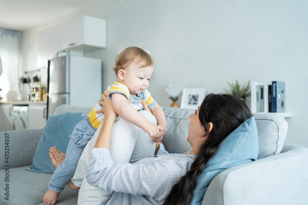 爱高加索的妈妈在客厅的沙发上和男婴玩耍。