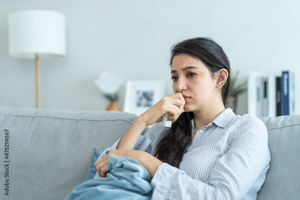 亚洲美丽的不幸女人坐在沙发上感到沮丧和压力